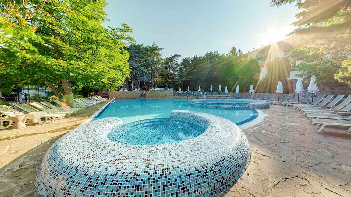 Ulkoallas, jossa aurinkotuoleja ja puita taustalla. (Tekoälyn luoma teksti)