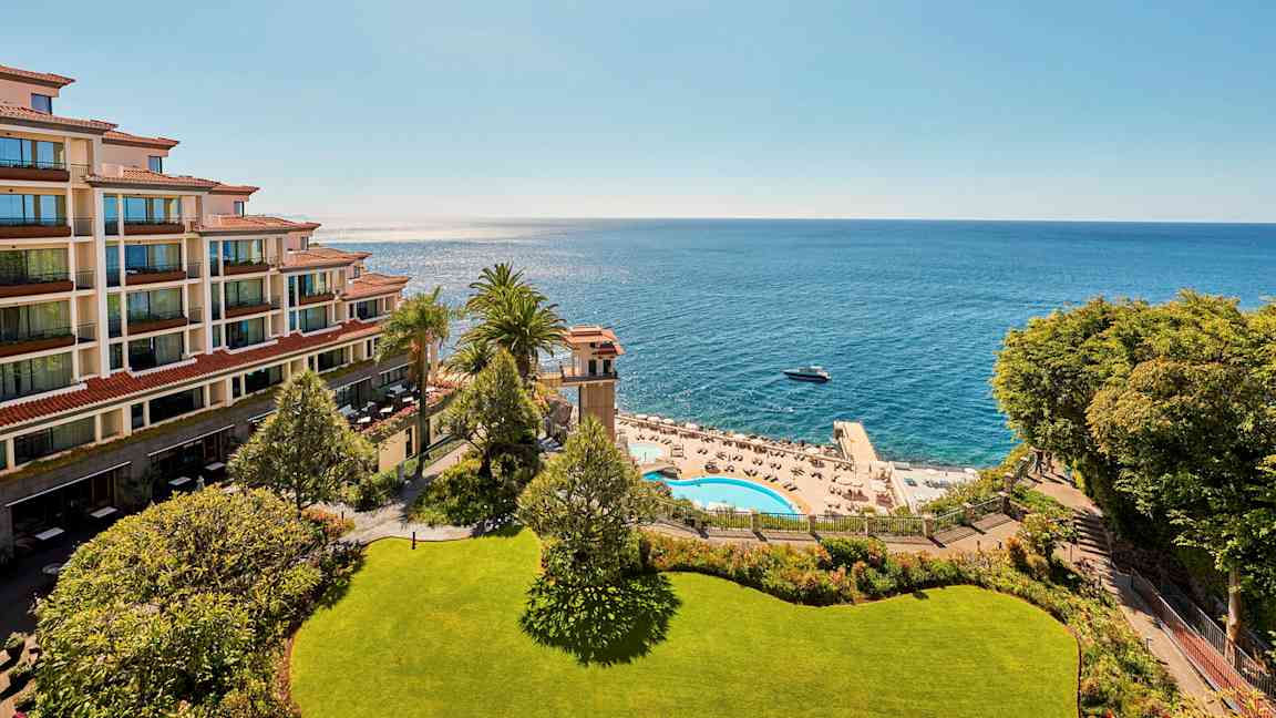 Kuva hotellista rannalla, merinäköala, allasalue ja aurinkotuoleja. (Tekoälyn luoma teksti)