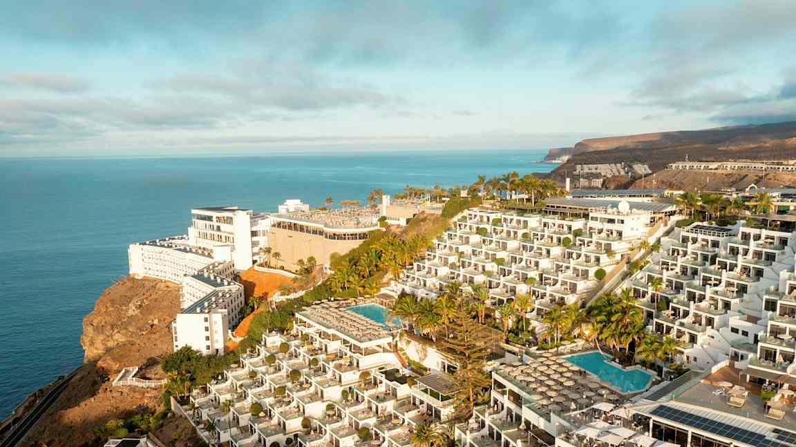 Hotellikompleksi kalliolla, jossa on uima-altaita ja merinäköala. (Tekoälyn luoma teksti)