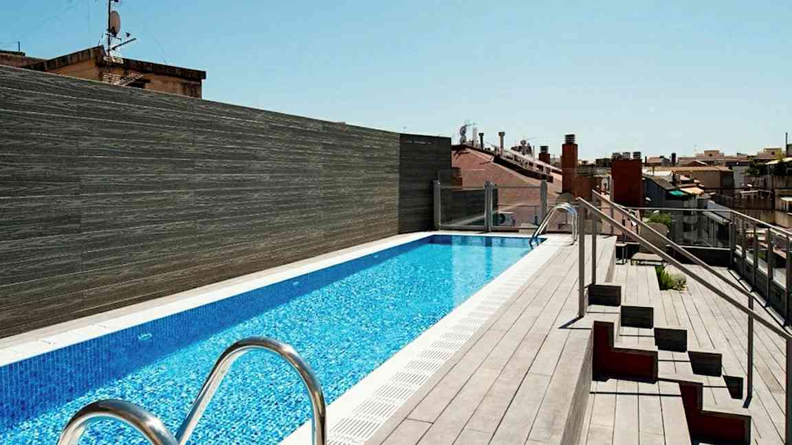 Kattoterassi, jossa on pitkä uima-allas, jota ympäröi terassilattia ja vieressä istuimia. (Tekoälyn luoma teksti)