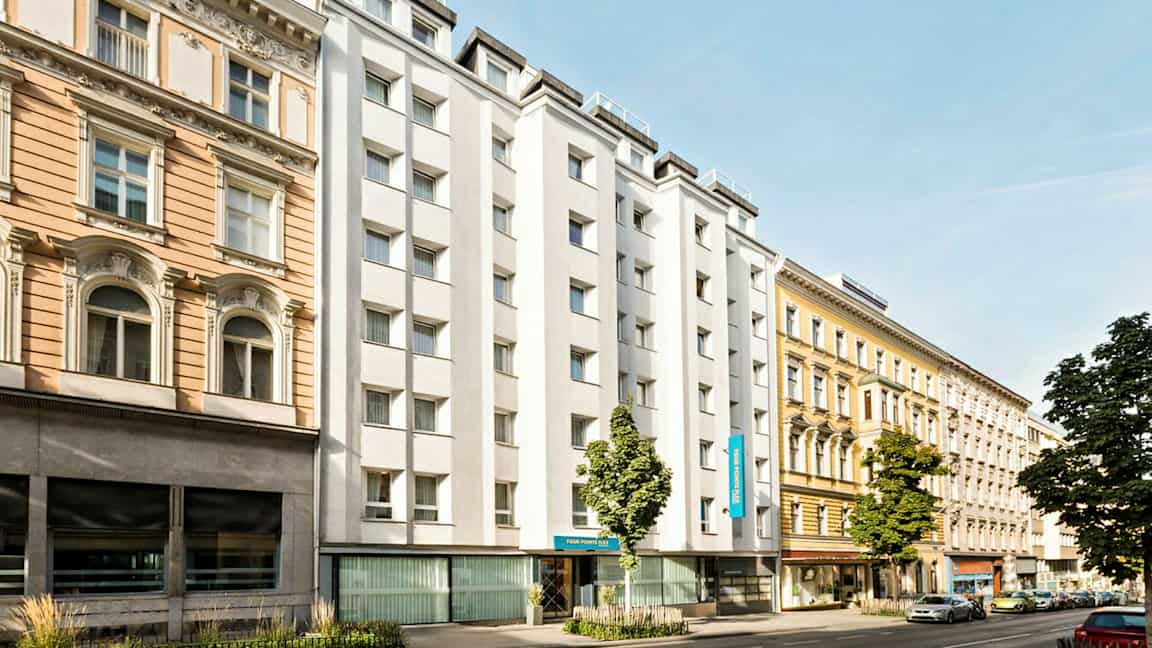 Kaupunkikatu, jossa on eri vuosikymmenten rakennuksia, mukaan lukien valkoseinäinen hotelli. (Tekoälyn luoma teksti)