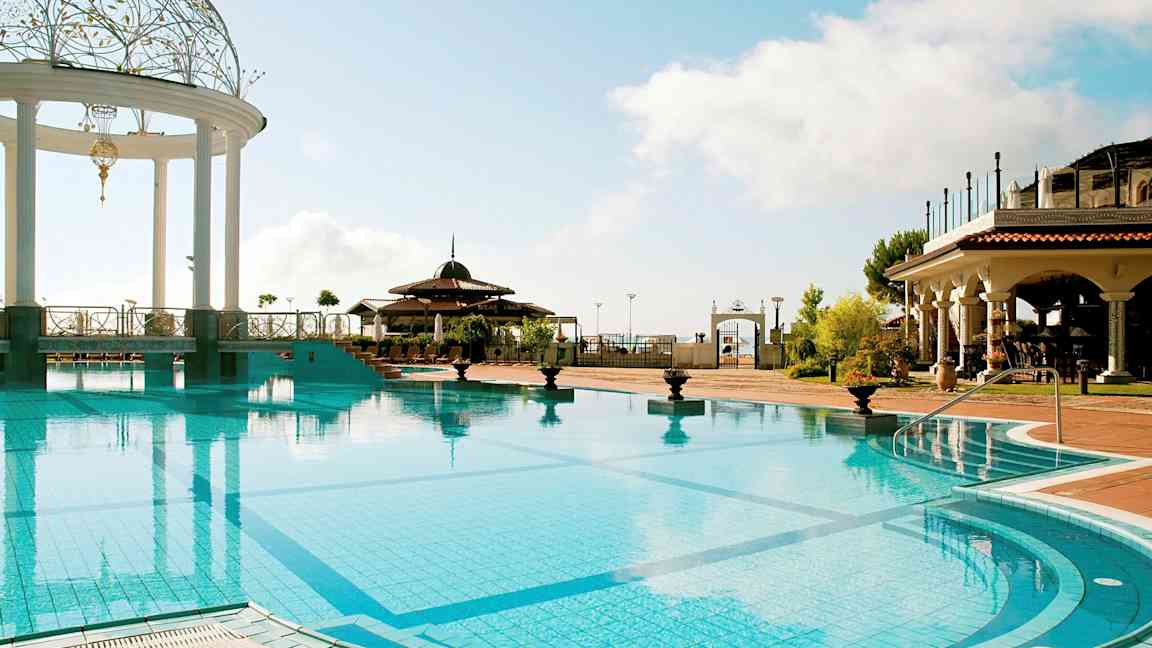 Ulkouima-allas, jossa koristeltu paviljonki ja ympärillä välimerellisiä rakennuksia. (Tekoälyn luoma teksti)