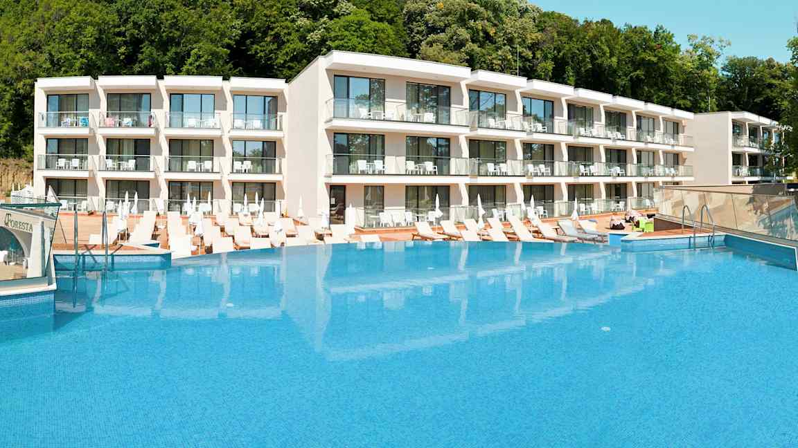 Hotellikompleksi, jonka edessä suuri uima-allas ja ympärillä aurinkotuoleja. (Tekoälyn luoma teksti)