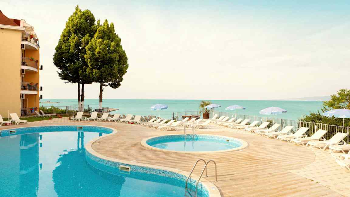 Kaksi uima-allasta aurinkotuoleilla ja varjoilla paikan lähellä merta. (Tekoälyn luoma teksti)