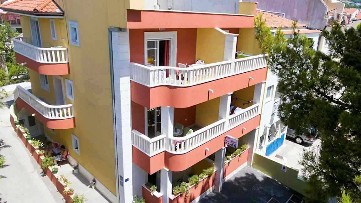 Rakennus, jossa on keltainen ja punainen julkisivu, parvekkeet ja pieni sisäpiha. (Tekoälyn luoma teksti)