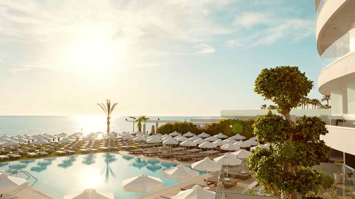 Ulkouima-allas, aurinkotuoleja ja varjoja, taustalla meri. (Tekoälyn luoma teksti)