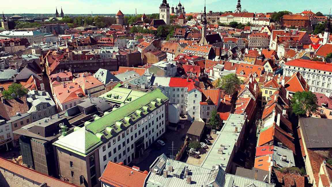 Kaupunkinäkymä ilmasta, jossa on vanhoja erivärisiä rakennuksia. (Tekoälyn luoma teksti)