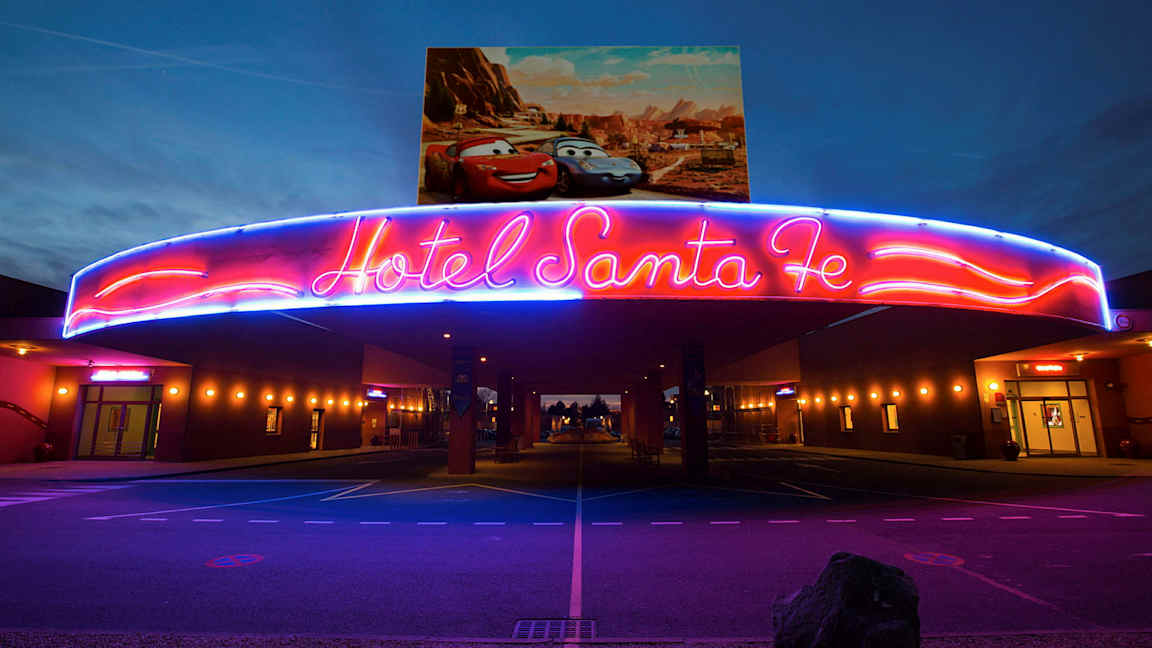 Hotel Santa Fen sisäänkäynnin yläpuolella oleva neonvalaistus, jonka yläpuolella on Disney/Pixar-autojen juliste. (Tekoälyn luoma teksti)