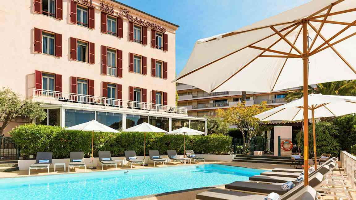 Hotellirakennus, jonka edessä on uima-allas ja aurinkotuoleja. (Tekoälyn luoma teksti)