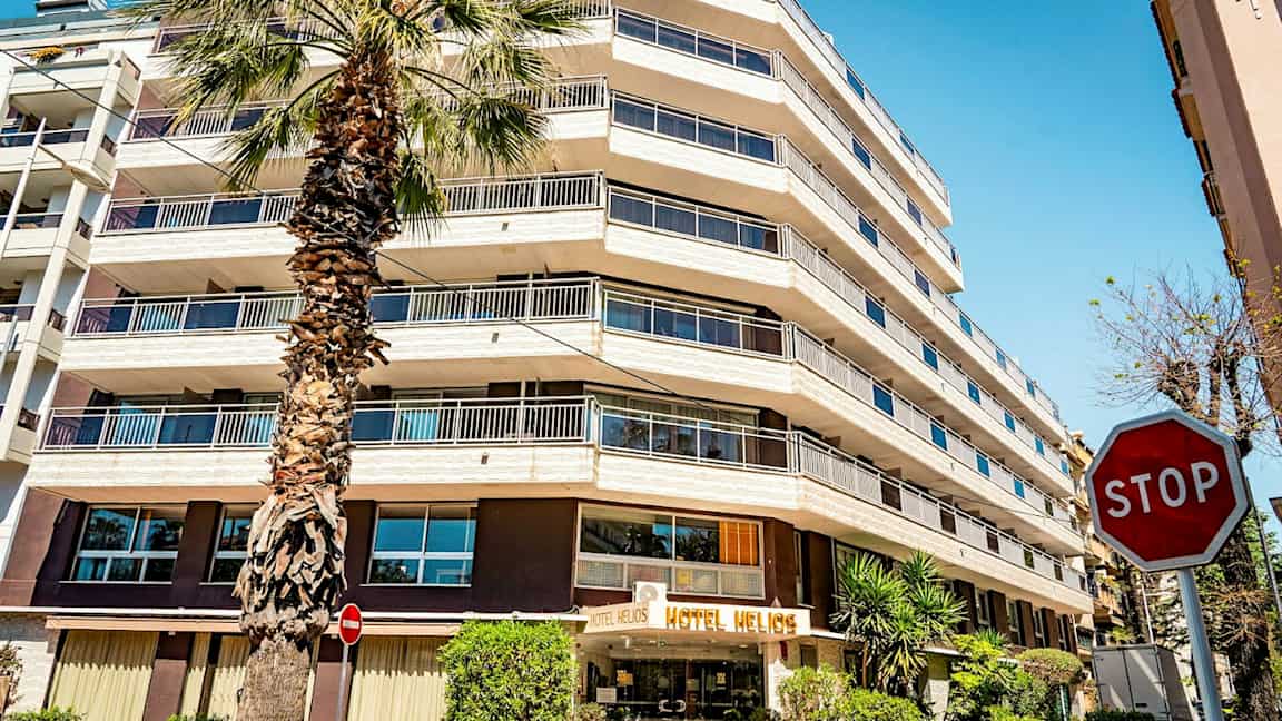 Monikerroksinen hotelli ja edessä oleva palmupuu. Oikealla näkyy "STOP"-merkki. (Tekoälyn luoma teksti)