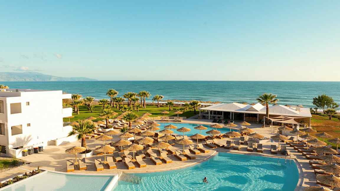 Uima-allasalue aurinkotuoleilla ja varjoilla, näkymä merelle. (Tekoälyn luoma teksti)