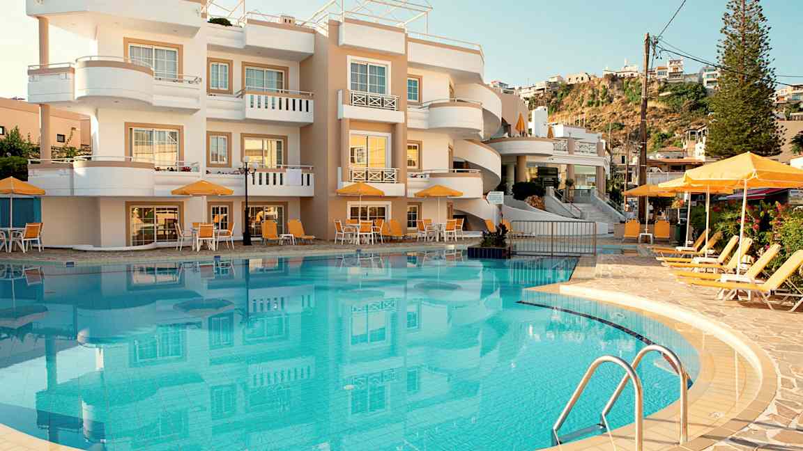 Kuva hotellista, jonka edessä on uima-allas ja aurinkotuoleja. (Tekoälyn luoma teksti)