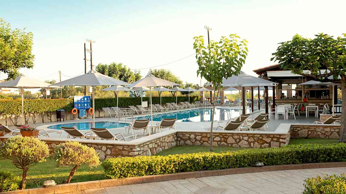 Uima-allas, jota ympäröivät aurinkotuolit, aurinkovarjot ja vehreys. (Tekoälyn luoma teksti)