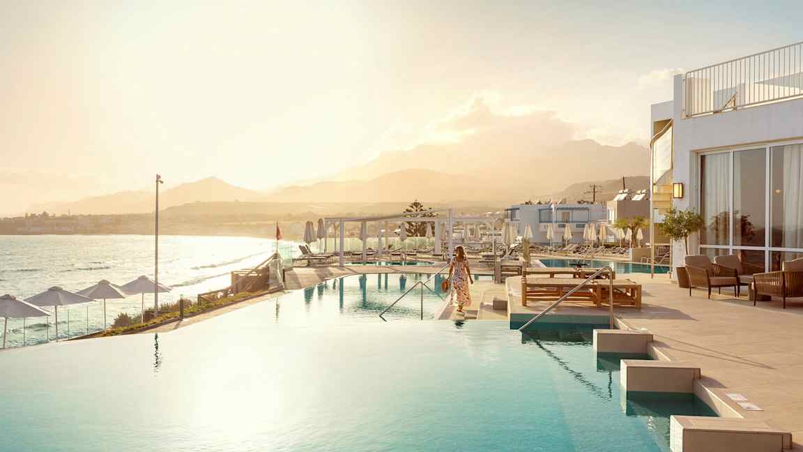 Nainen infinity-altaan vieressä, taustalla meri ja vuoristo. (Tekoälyn luoma teksti)