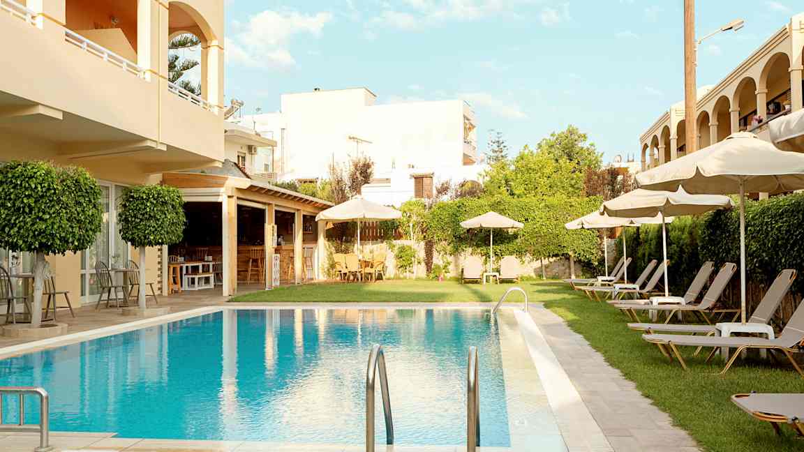 Hotellialue, jossa uima-allas, aurinkotuoleja ja aurinkovarjoja. (Tekoälyn luoma teksti)