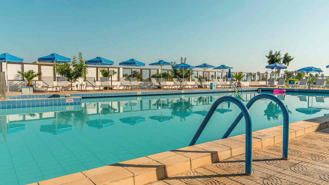 Ulkoilma uima-allas, jonka ympärillä sinisiä aurinkovarjoja ja aurinkotuoleja. (Tekoälyn luoma teksti)