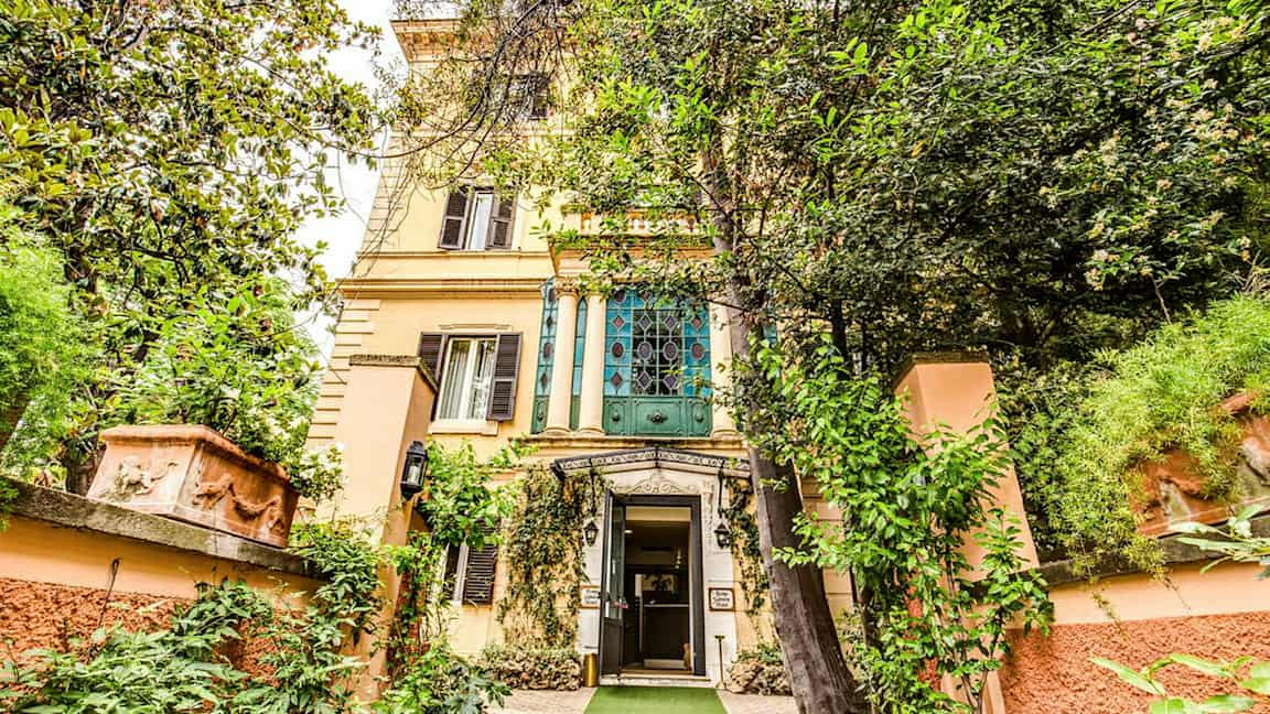 Rakennus, jossa on koristeellinen sisäänkäynti vihreyden keskellä. (Tekoälyn luoma teksti)