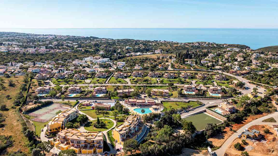 Ilmakuva lomakohteesta, jossa huviloita, uima-allas ja merinäköala. (Tekoälyn luoma teksti)