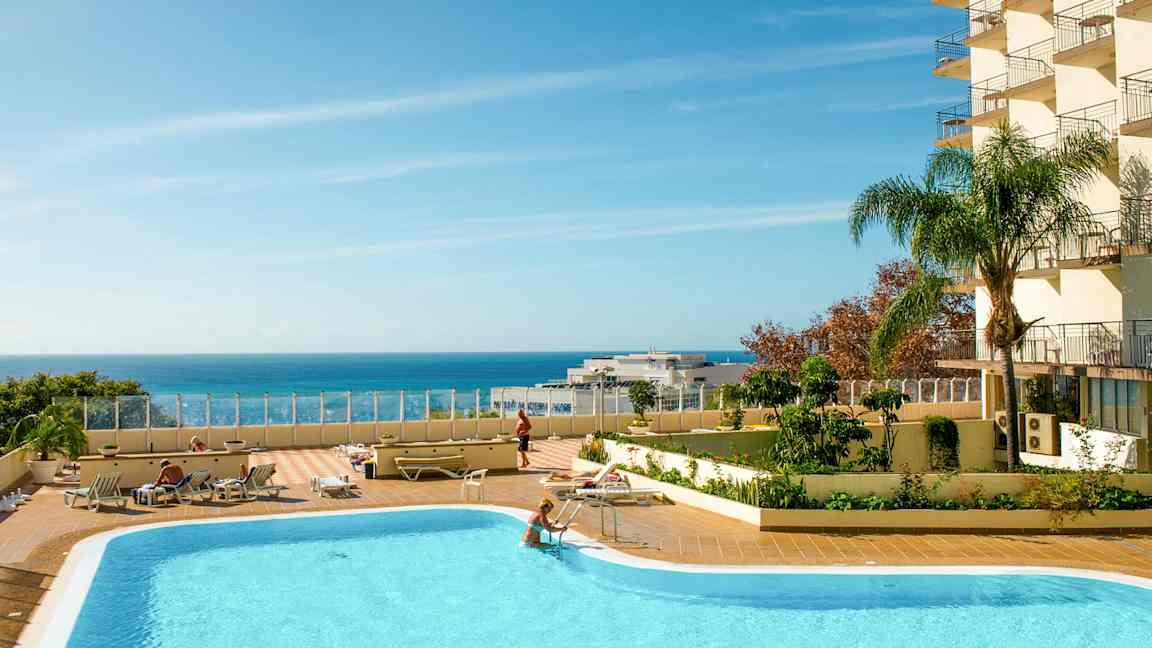 Ulkouima-allas aurinkotuoleineen ja kirkkaan sininen taivas meren yllä. (Tekoälyn luoma teksti)