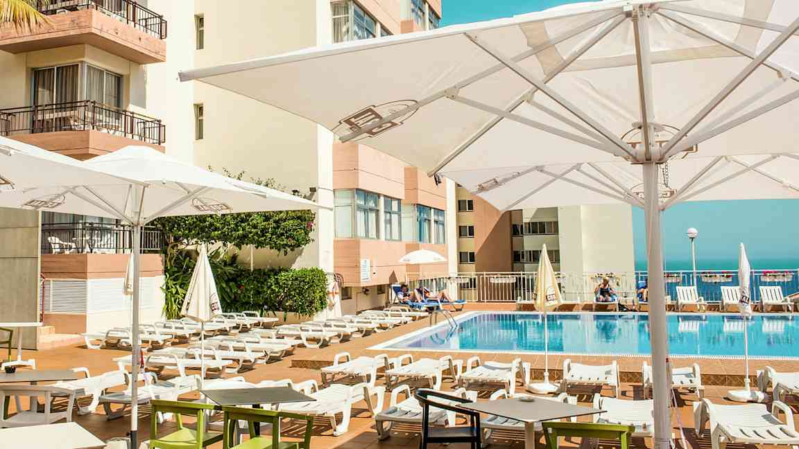 Ulkouima-allasalue, jossa on aurinkotuoleja ja aurinkovarjoja hotellin yhteydessä. (Tekoälyn luoma teksti)