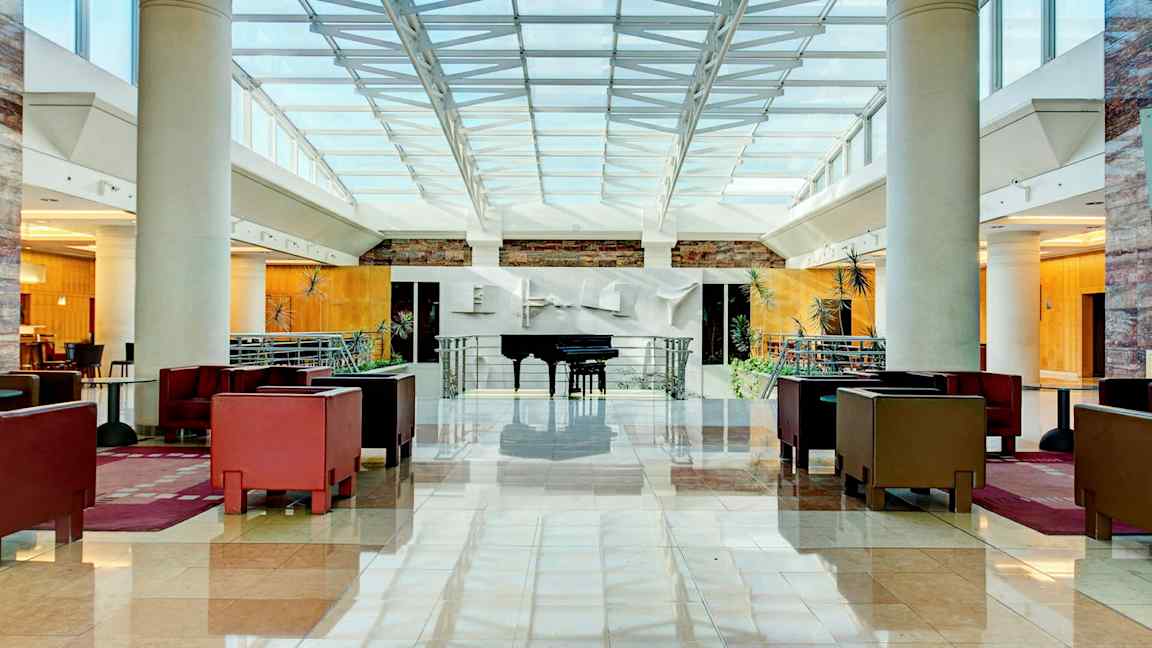 Valoisa ja tilava hotellin aula, jossa istuinryhmiä ja piano. (Tekoälyn luoma teksti)