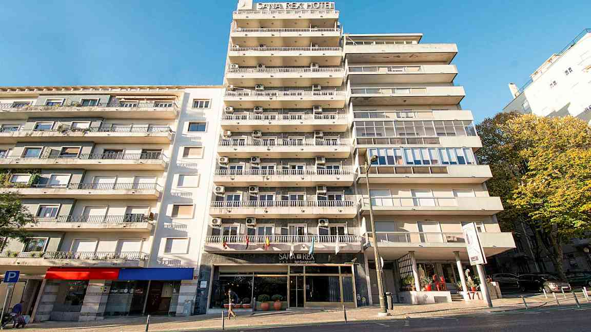 Kerrostalo, jossa hotellikyltti ja parvekkeet kirkkaan sinisen taivaan alla. (Tekoälyn luoma teksti)