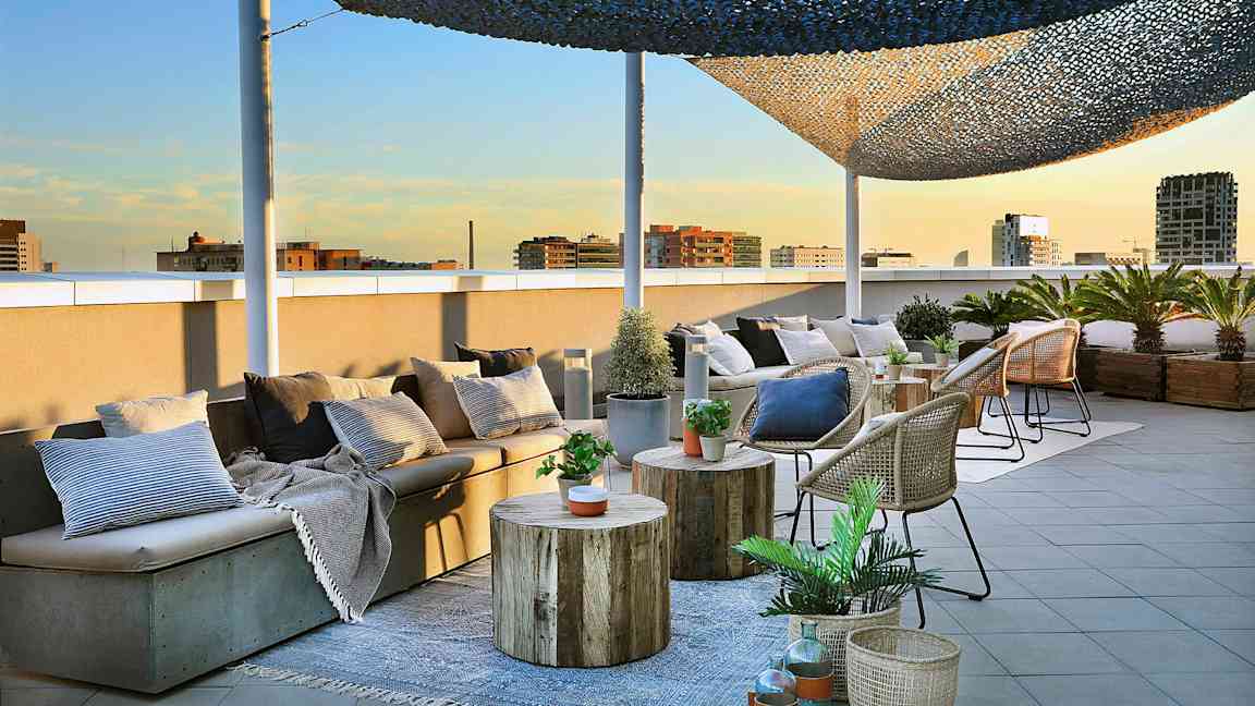 Kuvassa on kattoterassi, jossa on istuimia, pöytiä ja koreja koristeltuina kasveilla ja tyynyillä. (Tekoälyn luoma teksti)