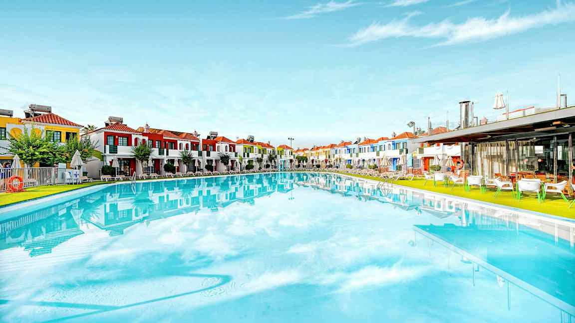 Suuri uima-allas, taustalla värikkäitä rakennuksia. (Tekoälyn luoma teksti)