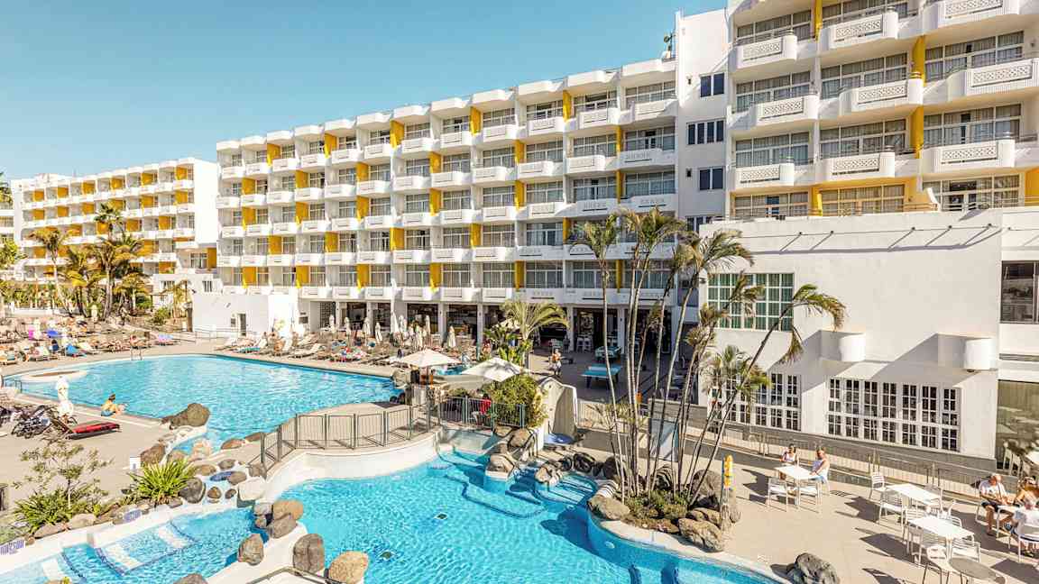 Hotellirakennus, aurinkotuoleja ja allasalue. (Tekoälyn luoma teksti)