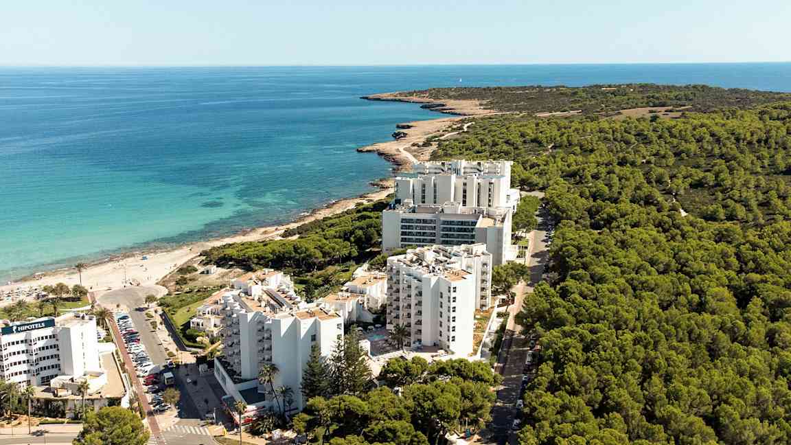 Ilmakuva rannikon hotellirakennuksista metsän edessä ja lähellä rantaa. (Tekoälyn luoma teksti)