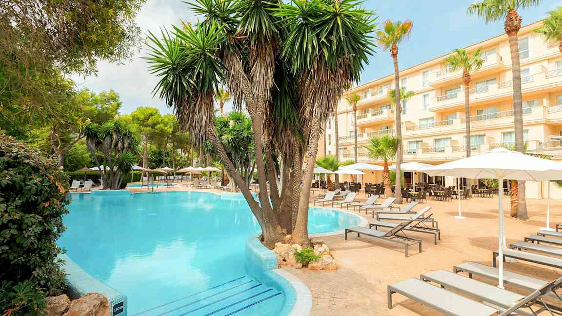 Hotellialue uima-altaalla, palmuilla ja aurinkotuoleilla. (Tekoälyn luoma teksti)