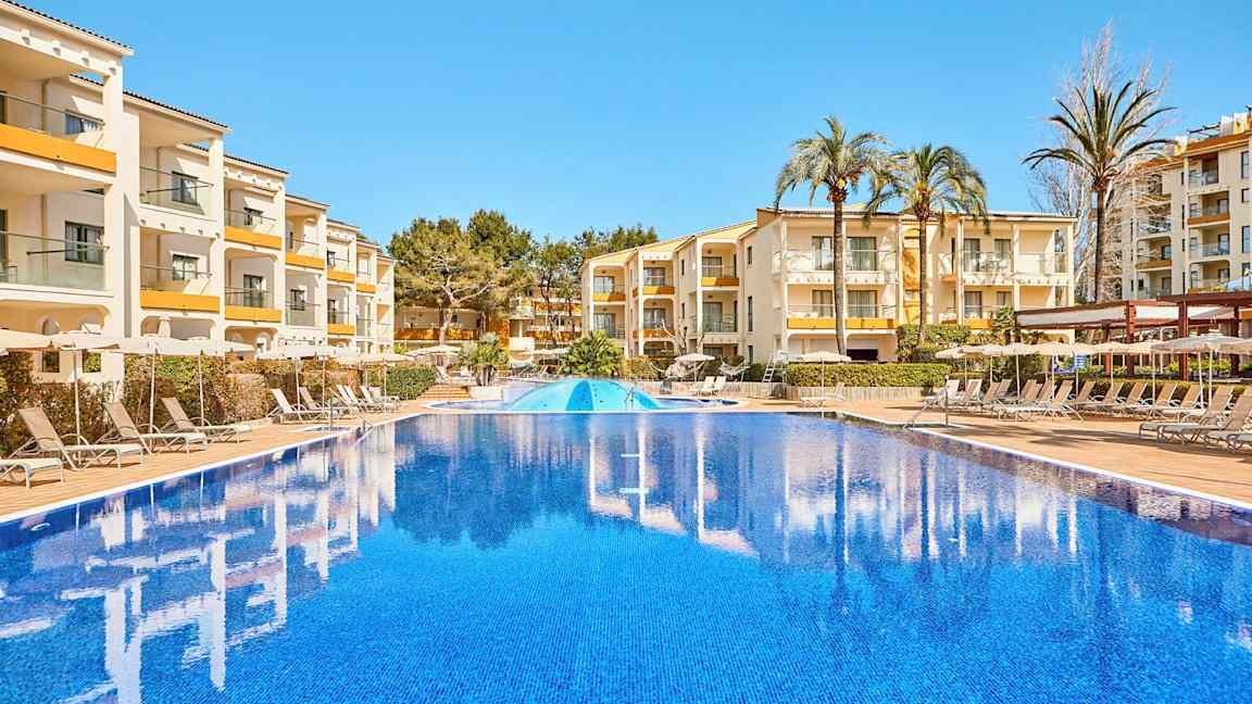 Kuva ulkouima-altaasta, taustalla rakennuksia ja aurinkotuoleja. (Tekoälyn luoma teksti)