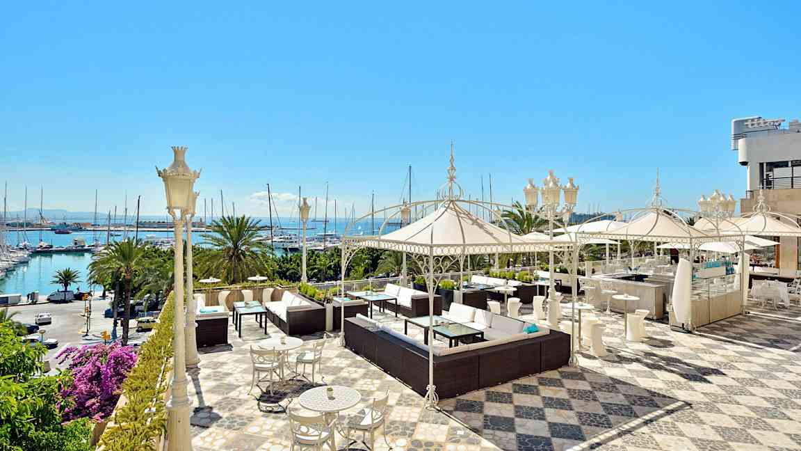 Tilava terassi, jossa on istuinryhmiä, aurinkovarjoja ja näkymä merelle. (Tekoälyn luoma teksti)