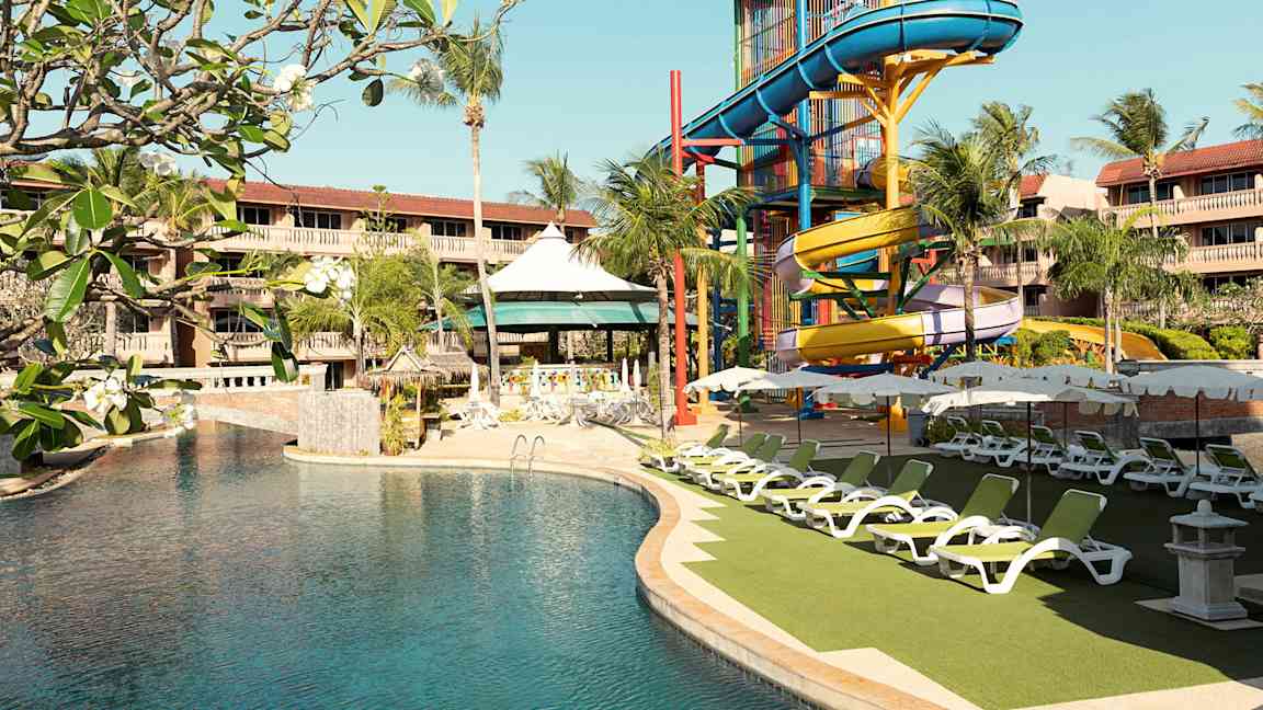 Hotellin uima-allas, jossa on värikäs vesiliukumäki ja aurinkotuoleja. (Tekoälyn luoma teksti)