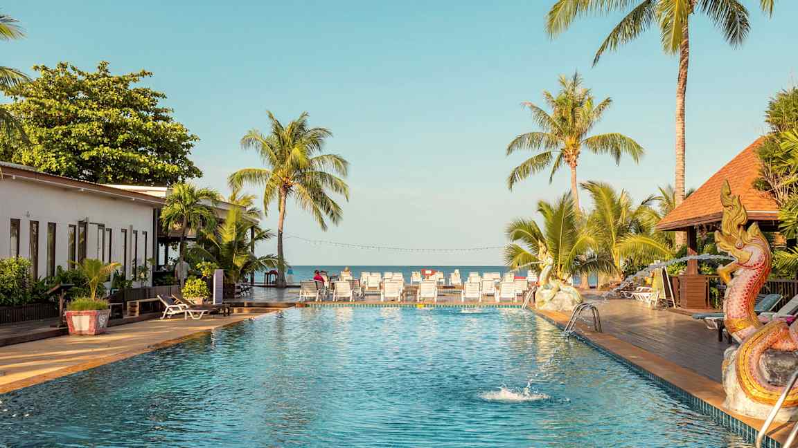 Uima-allas ulkona, taustalla palmuja ja aurinkotuoleja sekä altaan vieressä lohikäärmettä esittävä koriste. (Tekoälyn luoma teksti)