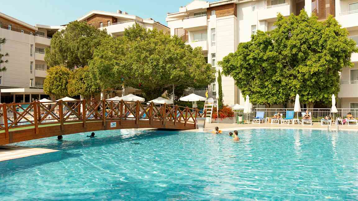 Ulkouima-allas, aurinkotuoleja ja puita taustalla. (Tekoälyn luoma teksti)