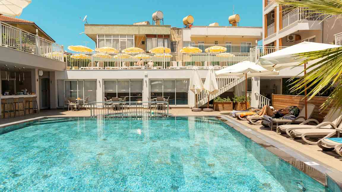 Ulkouima-allas, jota ympäröivät aurinkotuolit ja aurinkovarjot hotellilla. (Tekoälyn luoma teksti)