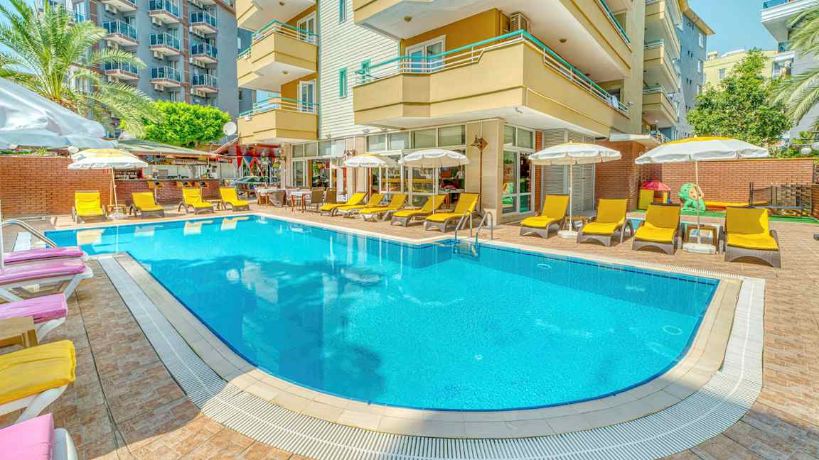 Ulkouima-allas, jota ympäröivät aurinkotuolit ja aurinkovarjot hotellirakennuksen edessä. (Tekoälyn luoma teksti)