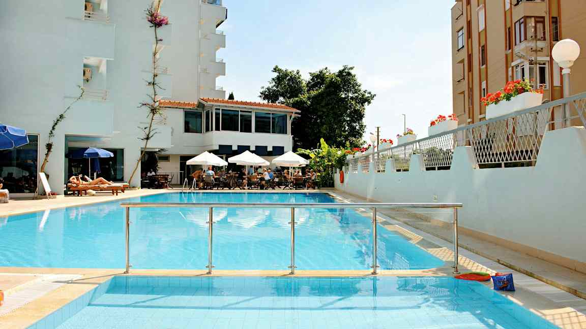 Kuva hotellista, jossa on uima-allas, istumaryhmä varjoilla ja aurinkotuoleja. (Tekoälyn luoma teksti)