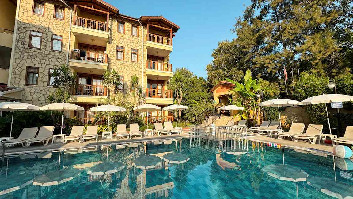 Hotellin julkisivu, edessä uima-allas ja aurinkotuoleja. (Tekoälyn luoma teksti)