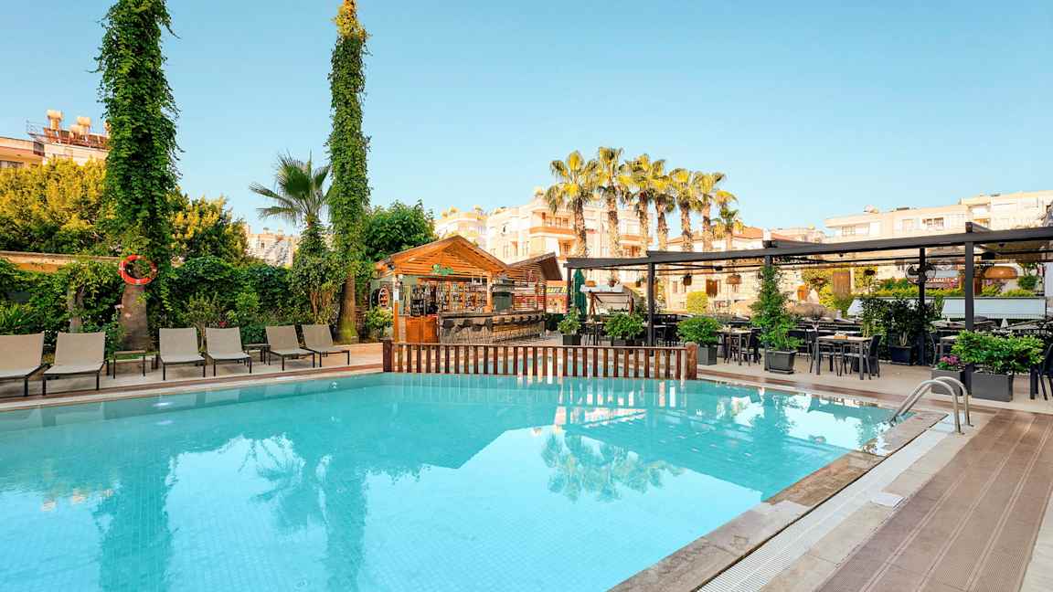 Ulkouima-allas, jossa aurinkotuoleja, puita ja baari taustalla. (Tekoälyn luoma teksti)