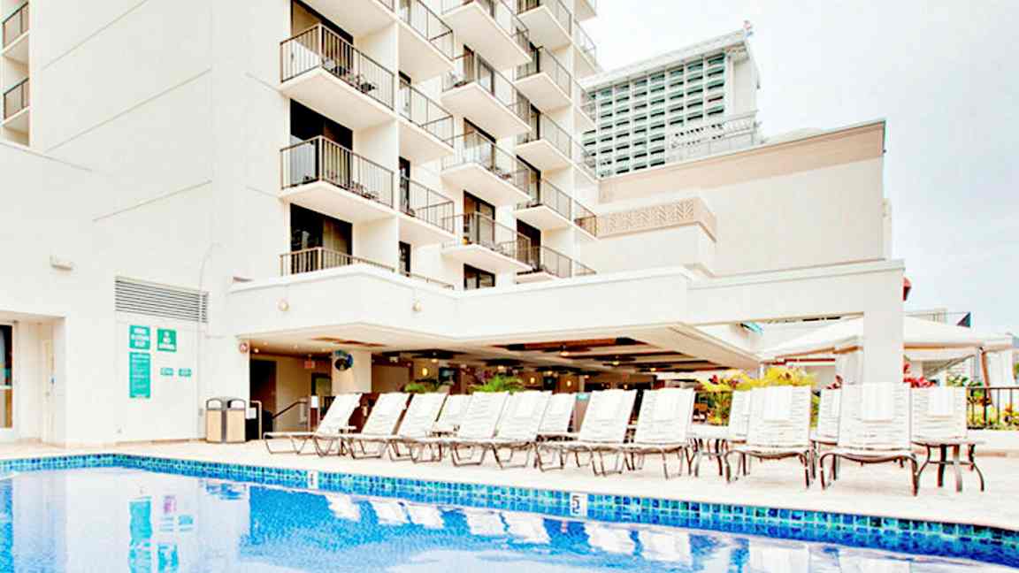 Kuva rakennuksesta, jossa on parvekkeita, uima-allas ja aurinkotuoleja. (Tekoälyn luoma teksti)