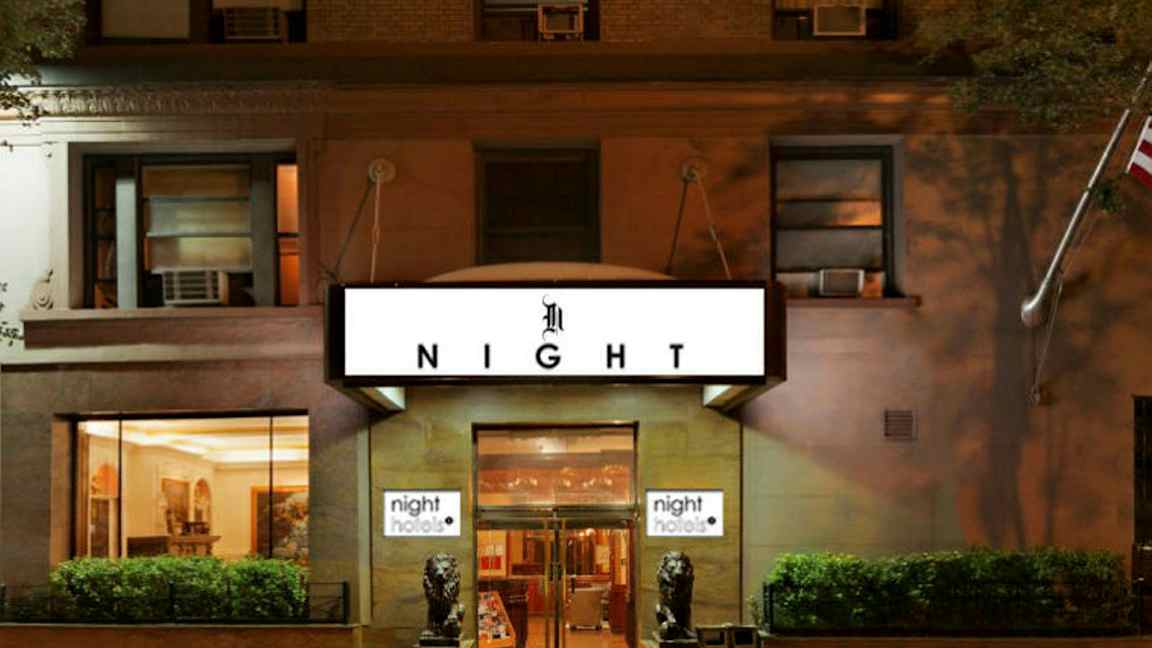 Hotellin julkisivu, jossa kyltti 'NIGHT', sisäänkäynnin edessä kaksi koristeltua leijonapatsasta. (Tekoälyn luoma teksti)