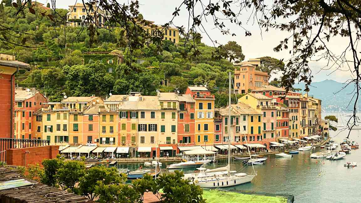 Satama, jossa on värikkäitä rakennuksia ja purjeveneitä vedessä. (Tekoälyn luoma teksti)