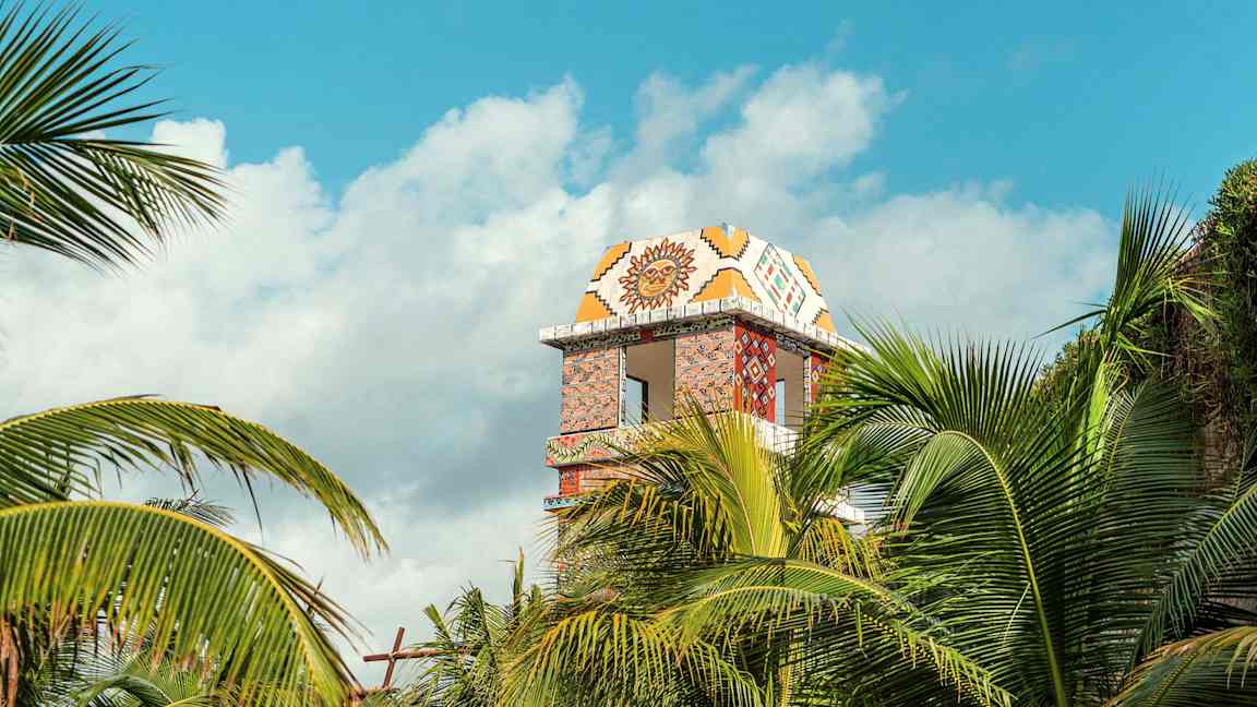 Koristeltu tornirakennus näkyvissä palmujen takana. (Tekoälyn luoma teksti)