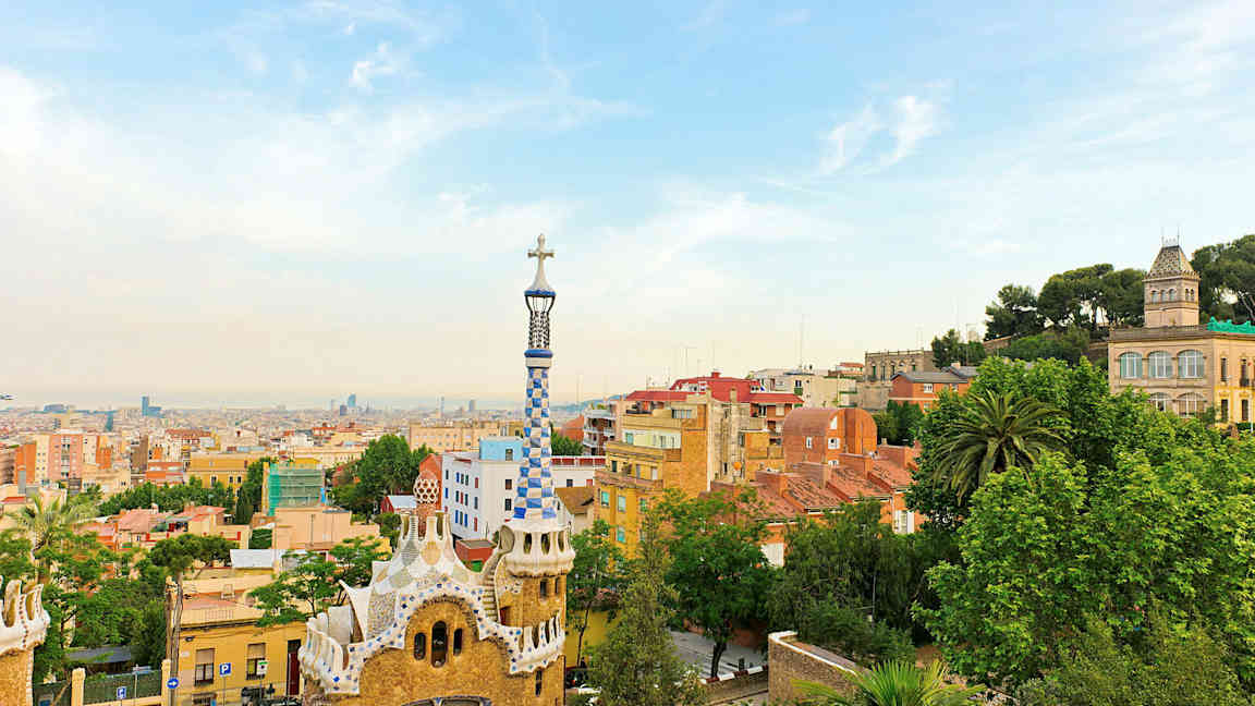 Näkymä Barcelonan Park Güellistä, jossa värikkäitä rakennuksia ja kaupungin siluetti taustalla. (Tekoälyn luoma teksti)