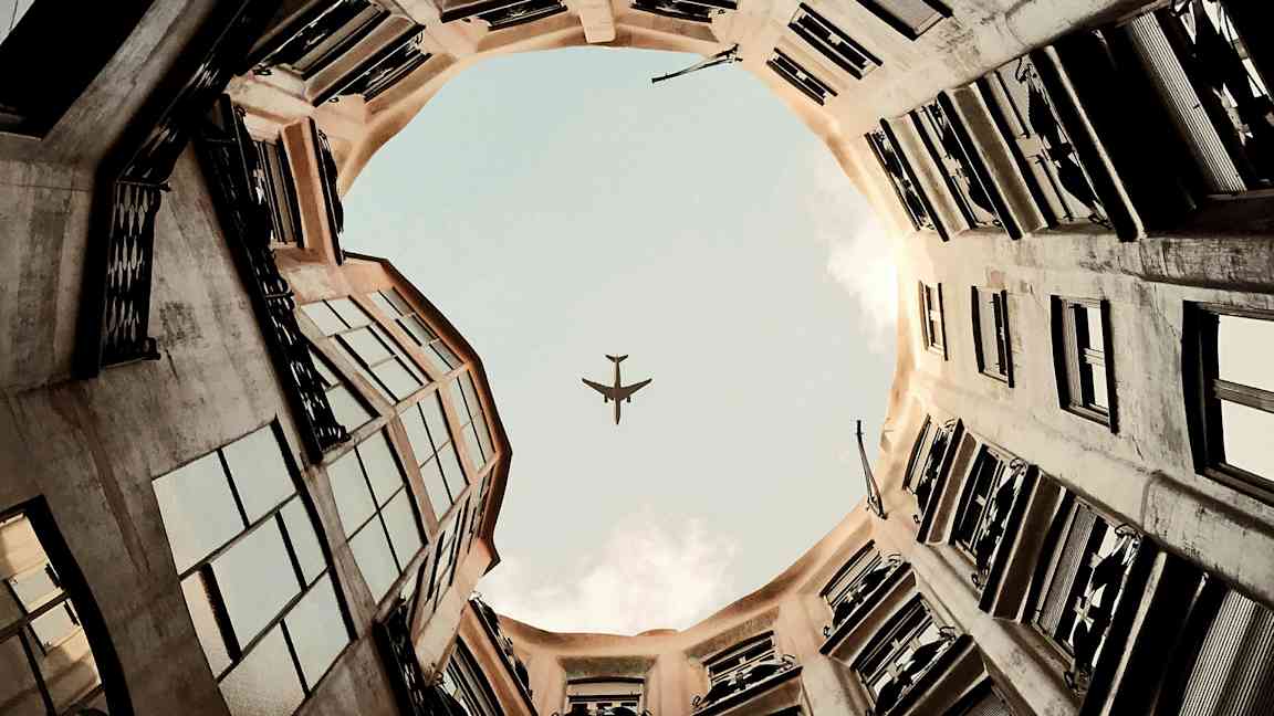 Kuva lentokoneen siluetista taivasta vasten rakennuksen sisäpihalta katsottuna. (Tekoälyn luoma teksti)