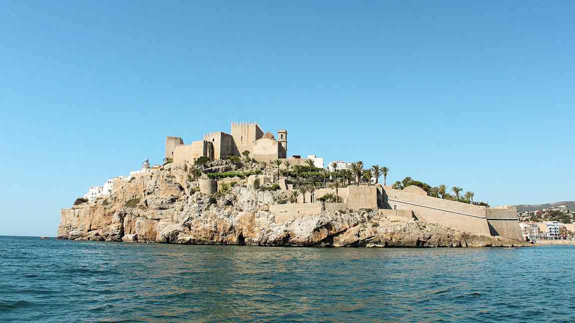 Linna ja rakennuksia kallion päällä meren äärellä, ympäröitynä palmupuilla. (Tekoälyn luoma teksti)