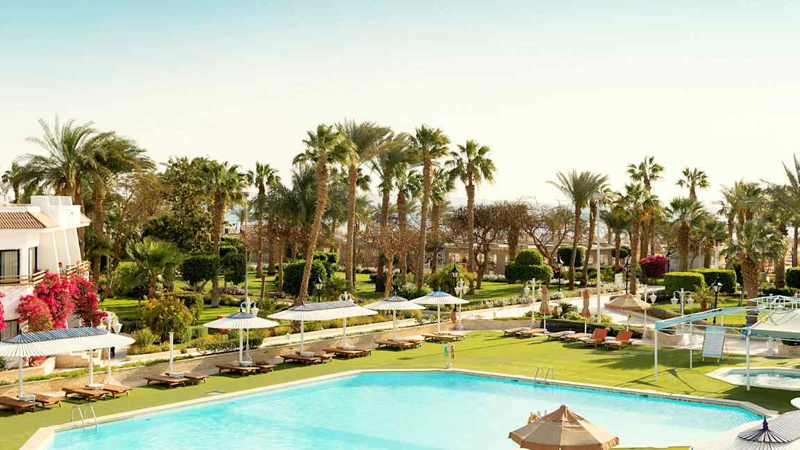 Uima-allas aurinkotuoleineen, varjoineen ja viheralueineen taustalla. (Tekoälyn luoma teksti)