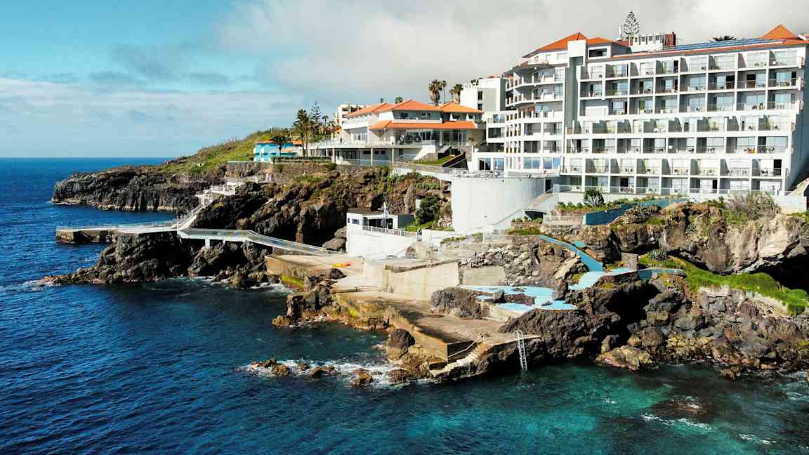 Hotellirakennuksia kallioilla, näkymä merelle ja allasalueille. (Tekoälyn luoma teksti)